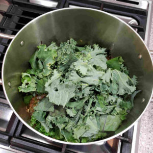 Add the rest of the stock, bring to a boil, and fold in the greens a few handfuls at a time.