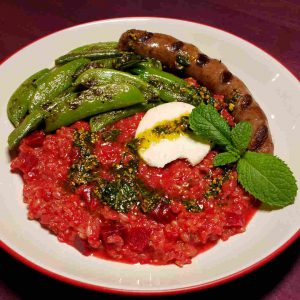 Beet Risotto Garnished with Mint Pistou and Chevre and Served with Sugar Snap Peas and Merguez Sausage