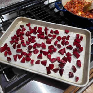 While the sauté continues, toss the chopped beets in olive oil with a pinch of salt, and spread on a baking tray.