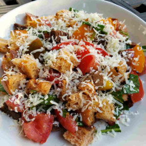 Panzanella with Tomatoes and Arugula Topped with Aged Asiago Style Cheese