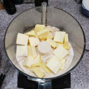 After mixing togther the flours and salt in a mixing bowl, put 2/3 of the mixture in the food processor and add the pats of butter.