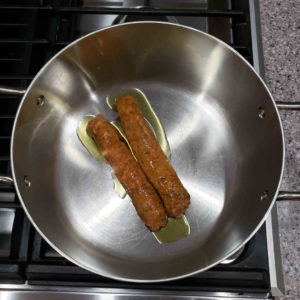 Remove the casing from two links of spicy Italian sausage and sauté them with some olive oil.