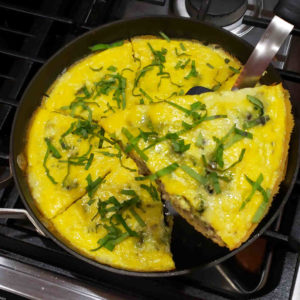 When the frittata has firmed up, remove from oven, optionally garnish with fresh herbs, and serve.