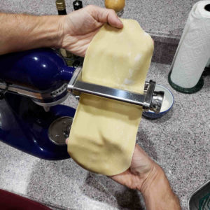 Rolling a sheet of fresh egg pasta.