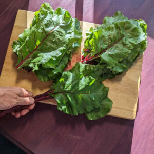 While the beet roots are roasting, separate the greens from the stems. Since the stems vary in length, I gather up about 5 or 6 at a time, lining them up at the base, and then either use a knife or kitchen scissors to separate them.