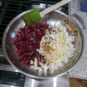Rinse the stems, and then dice them up. Also dice up a medium onion. Add them, along with salt, red pepper flakes, coriander and olive oil to a large skillet and sauté them.