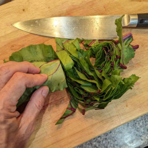 While the stems and onions sauté, prep the greens. I take stacks of leaves, roll them, and then slice them into ½” wide strips.